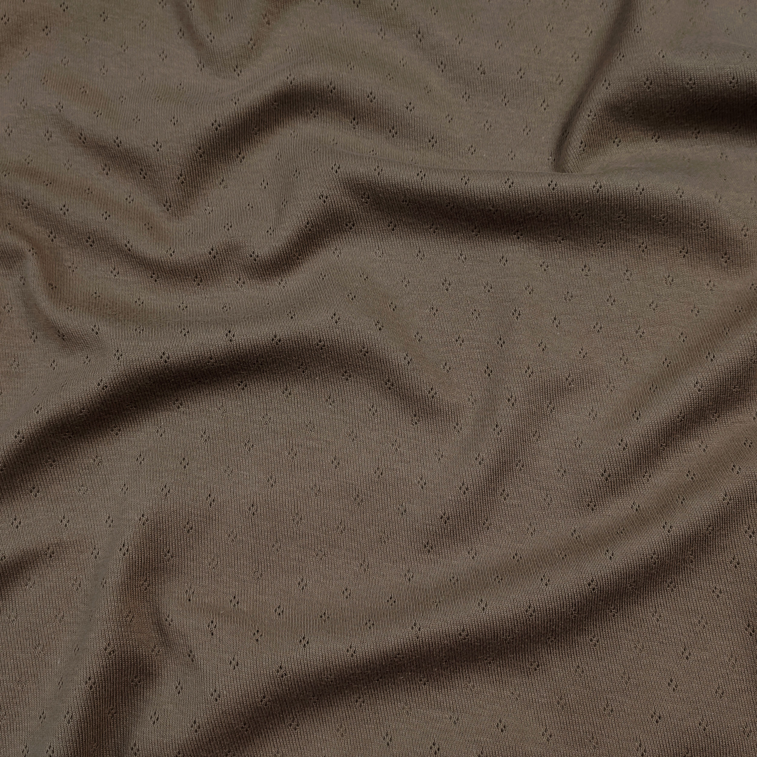 Flores perforadas en jersey de algodón sobre fondo beige oscuro